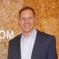 Man in a suit with no tie smiling at camera