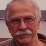 Image a man with a white mustache smiling at the camera